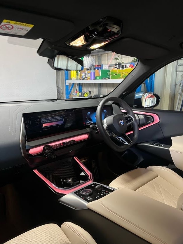 BMW interior with pink ambient lighting and protected cream leather seats