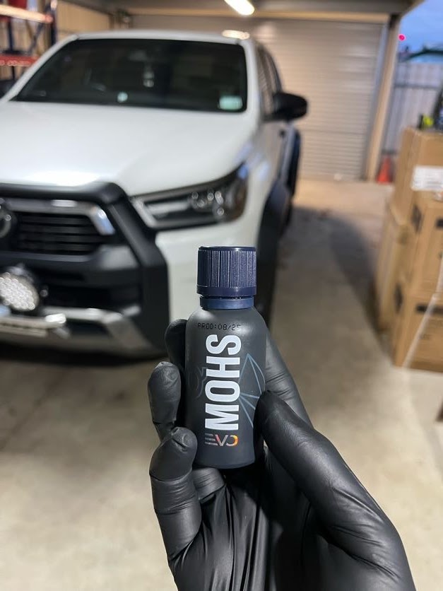 MOHS ceramic coating held in front of a white Toyota HiLux