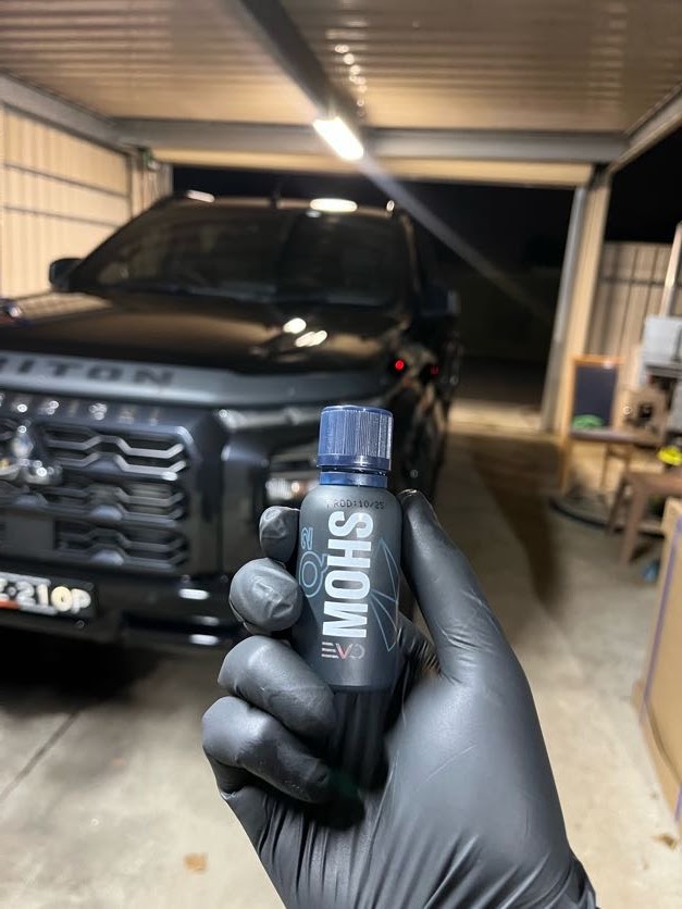 MOHS ceramic coating held in front of a black Mitsubishi Triton